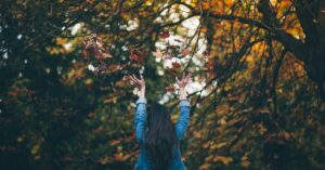 woman in fall surrounded by leaves