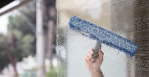 applying cleaning solution to residential window in New York City