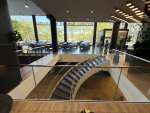 Multi‑level lobby with curved stair and floor‑to‑ceiling front windows — the kind of intricate surfaces that eat a DIY weekend.