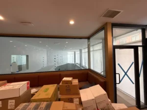 Interior workspace cluttered with boxes and cloudy glass walls, showing how neglected windows can dull even a modern space’s potential.