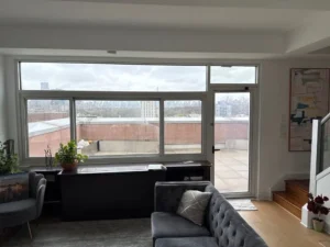 Bright city-facing living room with large windows, representing clarity, calm, and the post-cleaning satisfaction that sticks.