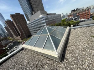 Low-angled shot of pyramid skylight on rooftop surrounded by urban high-rises in NYC