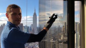 Andriy Mykyta inspecting hard water stains on high-rise window glass in Manhattan